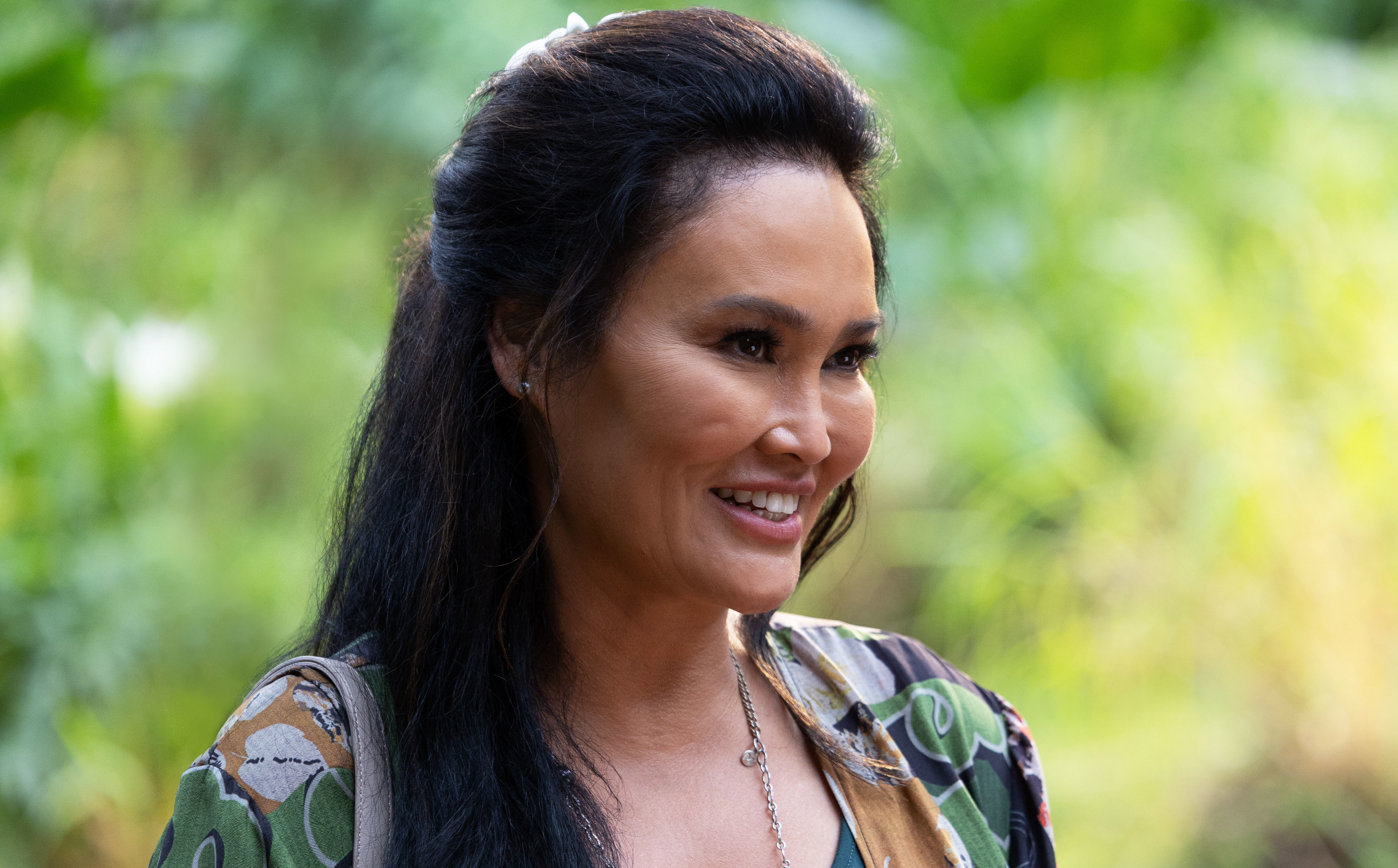 Tia Carrere smiles while standing among greenery in Lilo and Stitch.