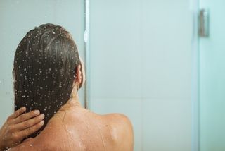 A woman stands in the shower.