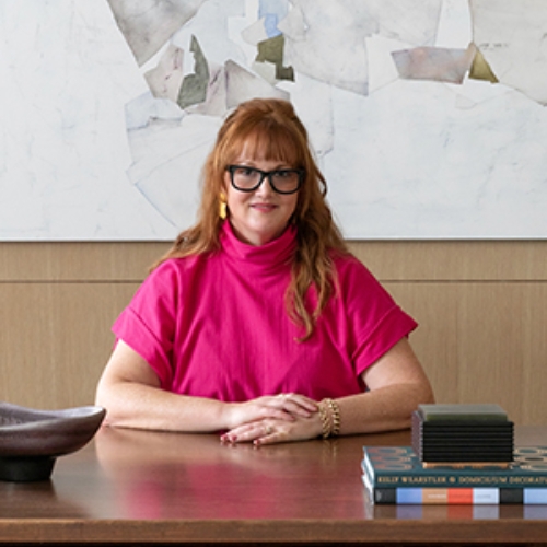 Image of a woman in a hot pink top sitting at a desk