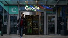 Google employee walks out of a company office in Warsaw, Poland, with Google branding and logo pictured above doorway.