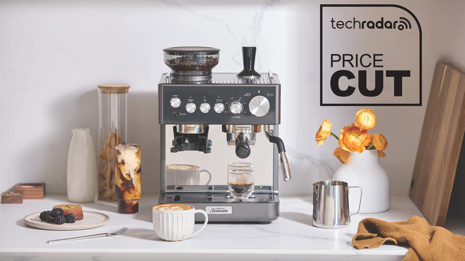 Sunbeam Origins Sense espresso machine on a kitchen counter, surrounded by coffee cups and milk jugs.