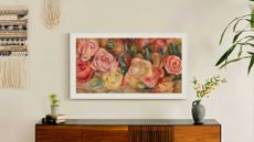 The Samsung Frame TV in art mode with a white bezel and bright artwork of blooms 