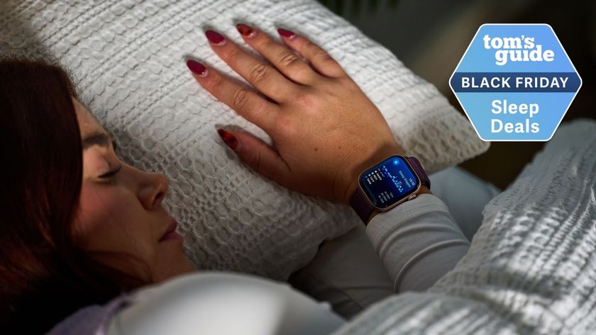 Our sleep tech reviewer in bed with white sheets wearing the Apple Watch Series 10 with purple strap displaying sleep stages screen on right wrist with Tom&#039;s Guide Black Friday sleep deals logo 