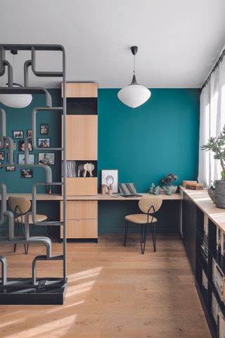 Study with wood flooring, green wall, black storage units and built in wooden desks and grey shelving