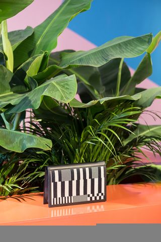 Clutch bag shown in front of green plants