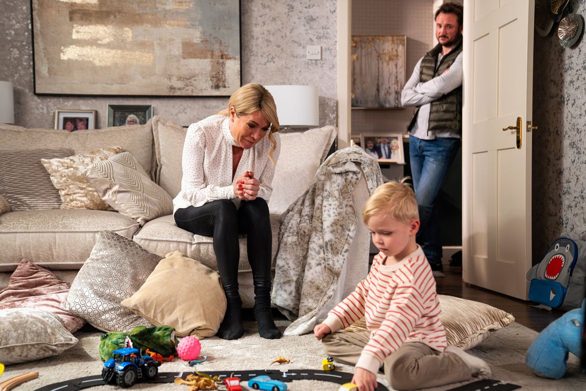 Sharon Watts sitting on the sofa watching Albie play with Martin Fowler standing in the doorway