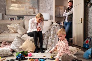 Sharon Watts sitting on the sofa watching Albie play with Martin Fowler standing in the doorway