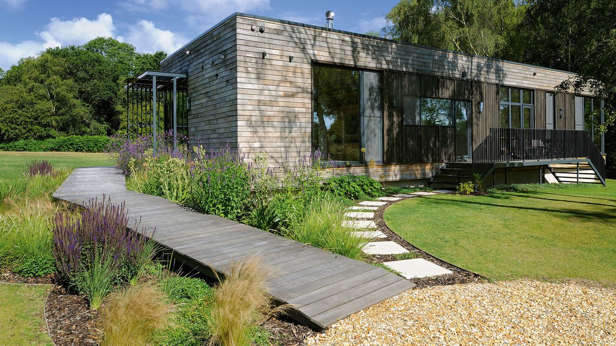 2 pathways leadign around a house. one decked boardwalk style and a stepping stone path