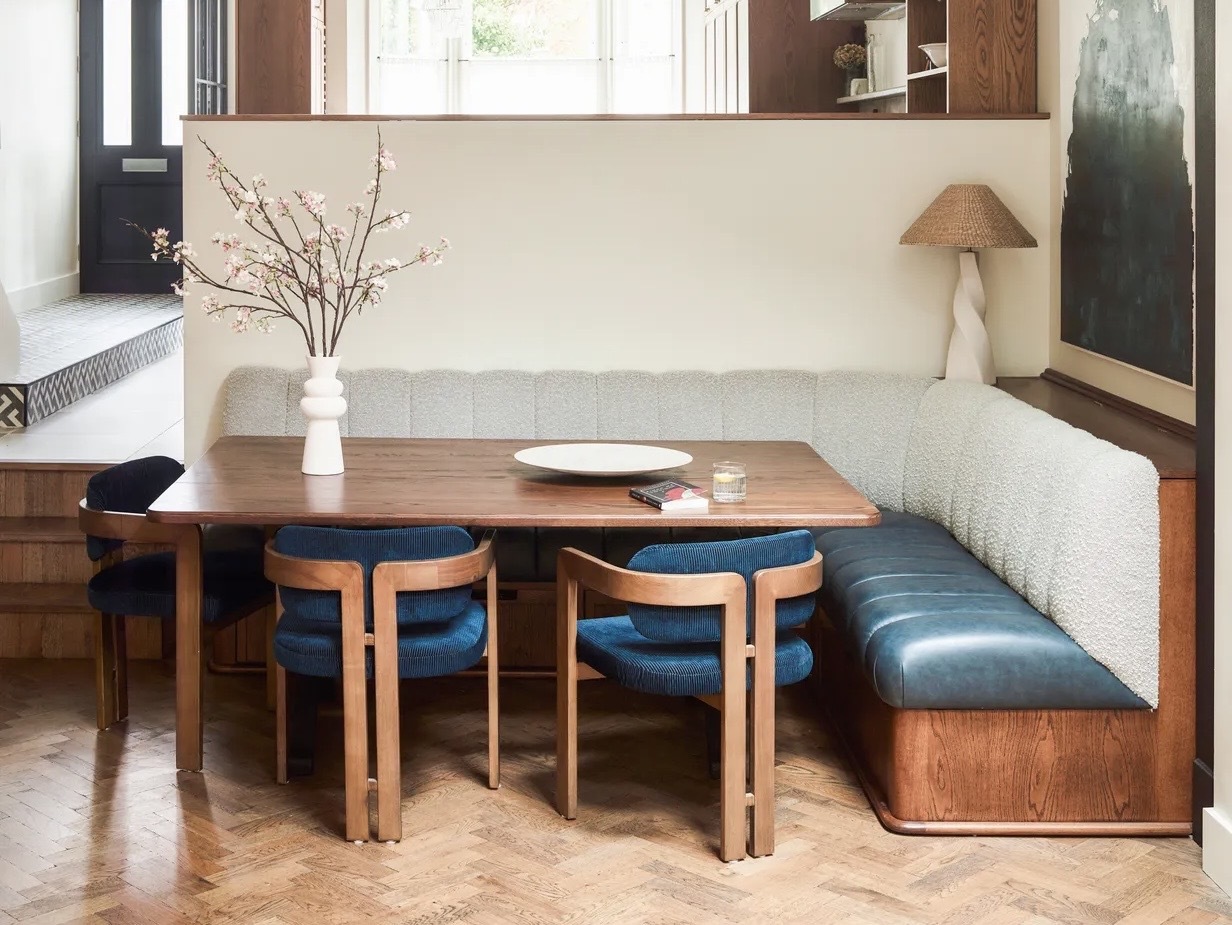 banquette seating and blue upholstered dining chairs in a split level dining space with parquet flooring and wood accents