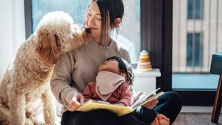 Woman reading to a baby with a dog by her side