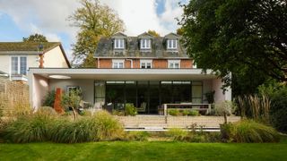 large modern living room extension on rear of large brick house with dormer windows in loft