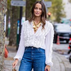 woman wearing embroidered white top and jeans