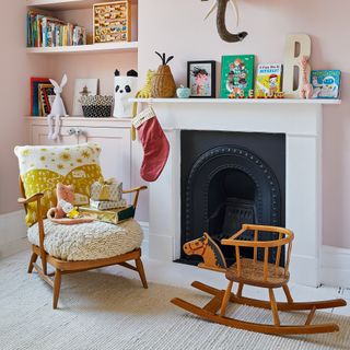 Pink nursery with wooden armchair and rocking horse
