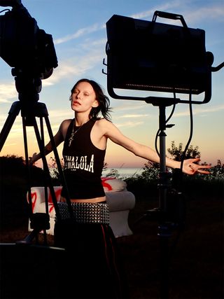 Musician Morgan Saint takes us behind-the-scenes of her "Kiss" video wearing a graphic black tank top and oversized studded belt.