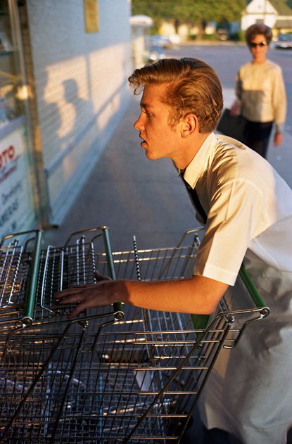 View of a grocery store clerk pushing grocery carts during the day