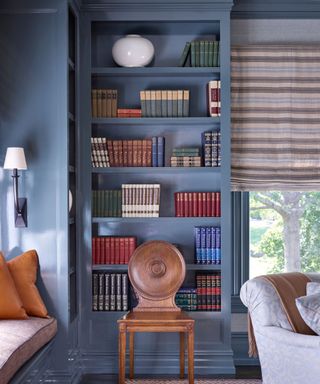 A study with bookshelves painted blue with vintage books