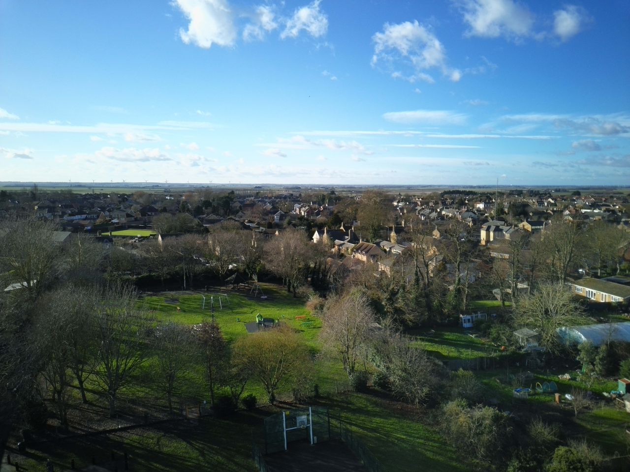 Aerial shot of a English town surrounded by trees and green fields