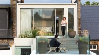 cream coloured loft conversion with sliding patio doors leading to roof terrace with planted areas and glass balustrade