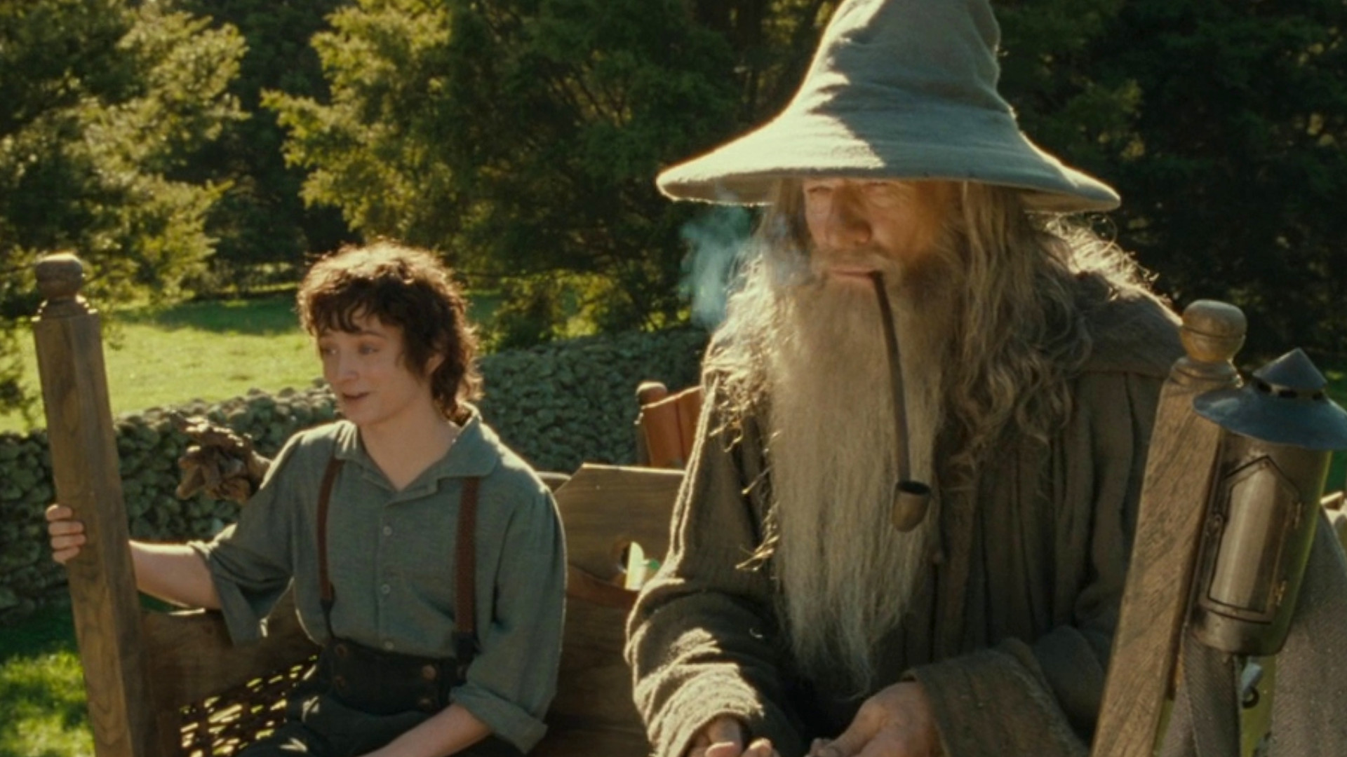 Elijah Wood as Frodo Baggins and Ian McKellen as Gandalf the Grey riding on a cart through the shire during The Lord of the Rings: The Fellowship of the Ring