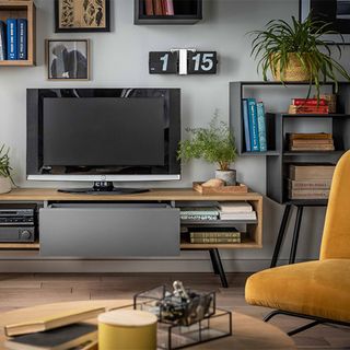 TV on console table in living room surrounded by wall storage