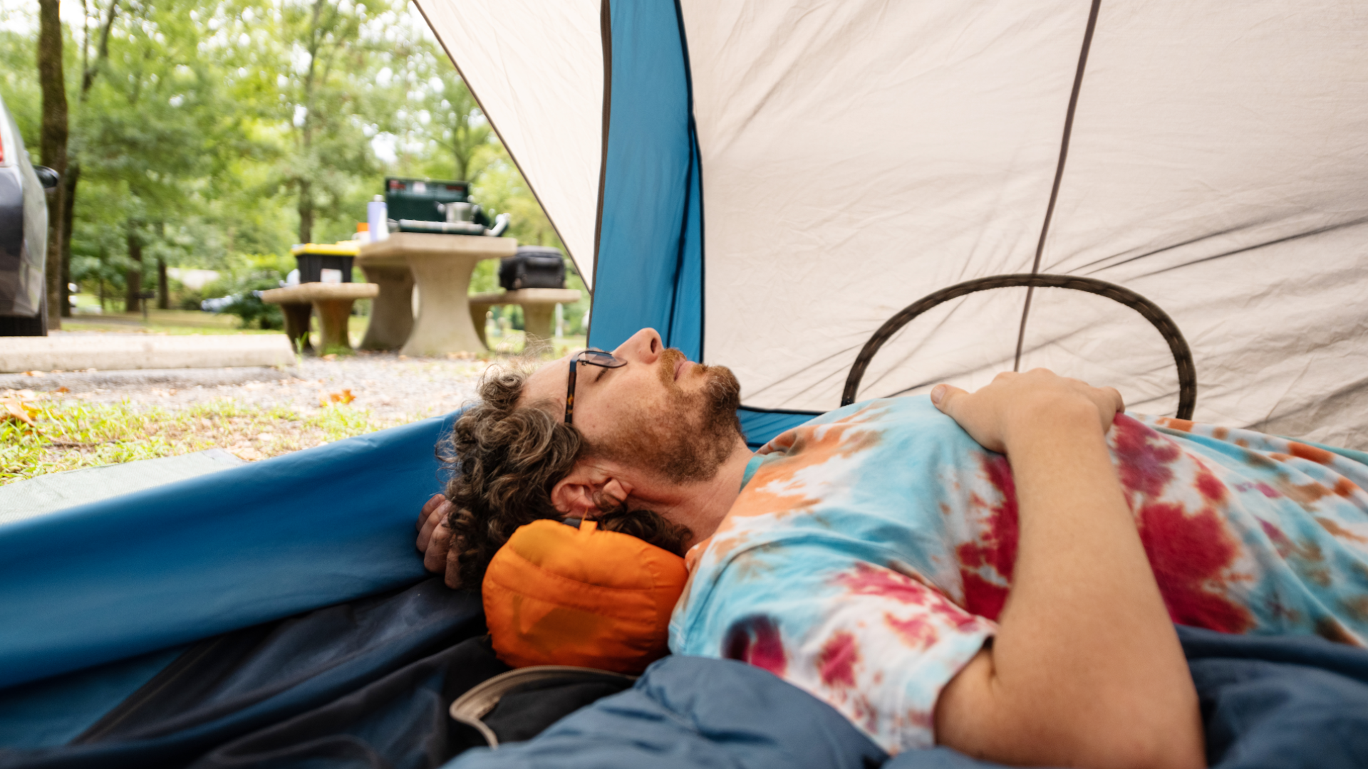 a man led down inside a tent with the door open, sleeping