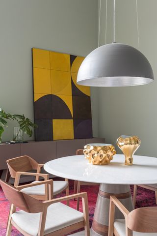 A dining space with olive green walls and a mustard artwork