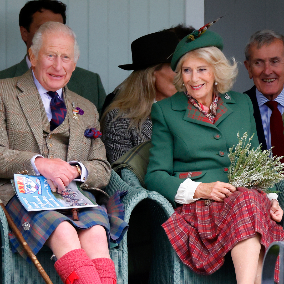King Charles and Queen Camilla wearing tweed jackets and kilts sitting next to each other