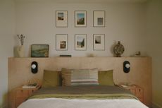 a bedroom with a plywood headboard and family photos on the wall behind, with green bedding on the bed