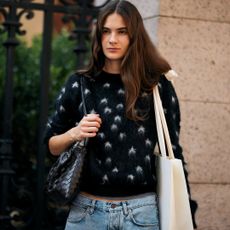 brunette woman wearing floral sweater and carrying tote bags