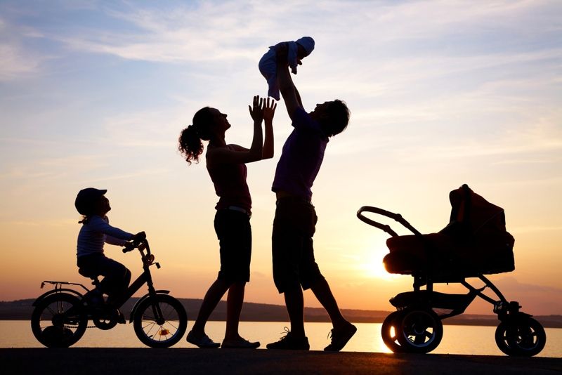 Silhouettes of happy parents having good time with their little children on the seacoast.