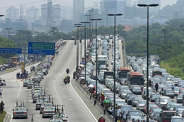 Gridlock: The peloton head towards Kuala Lumpur as traffic on the freeways comes to a standstill.