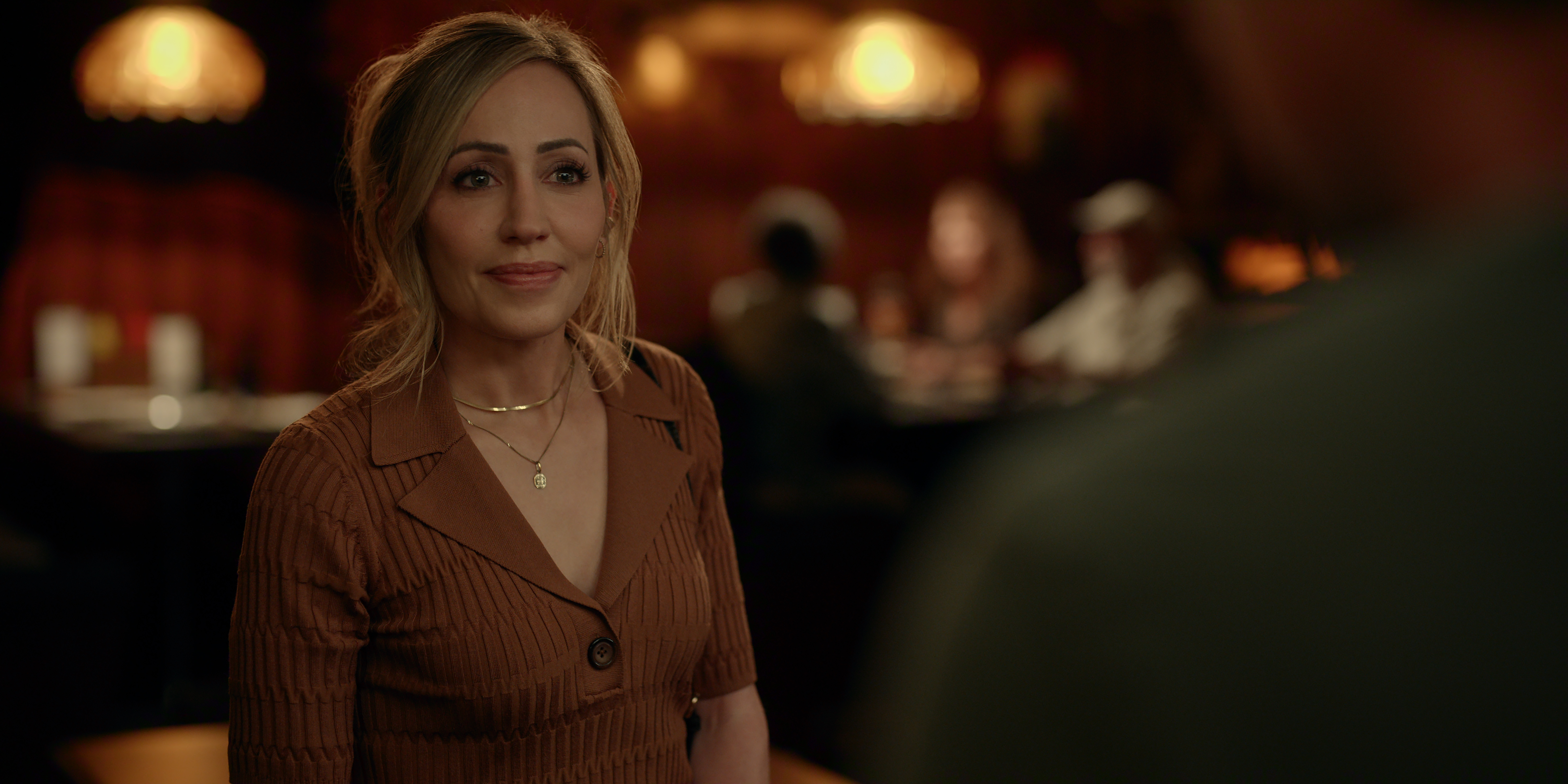 Zibby Allen as Brie Sheridan in Episode #705 of Virgin River Season 7 waering a brown top smiling while at a bar