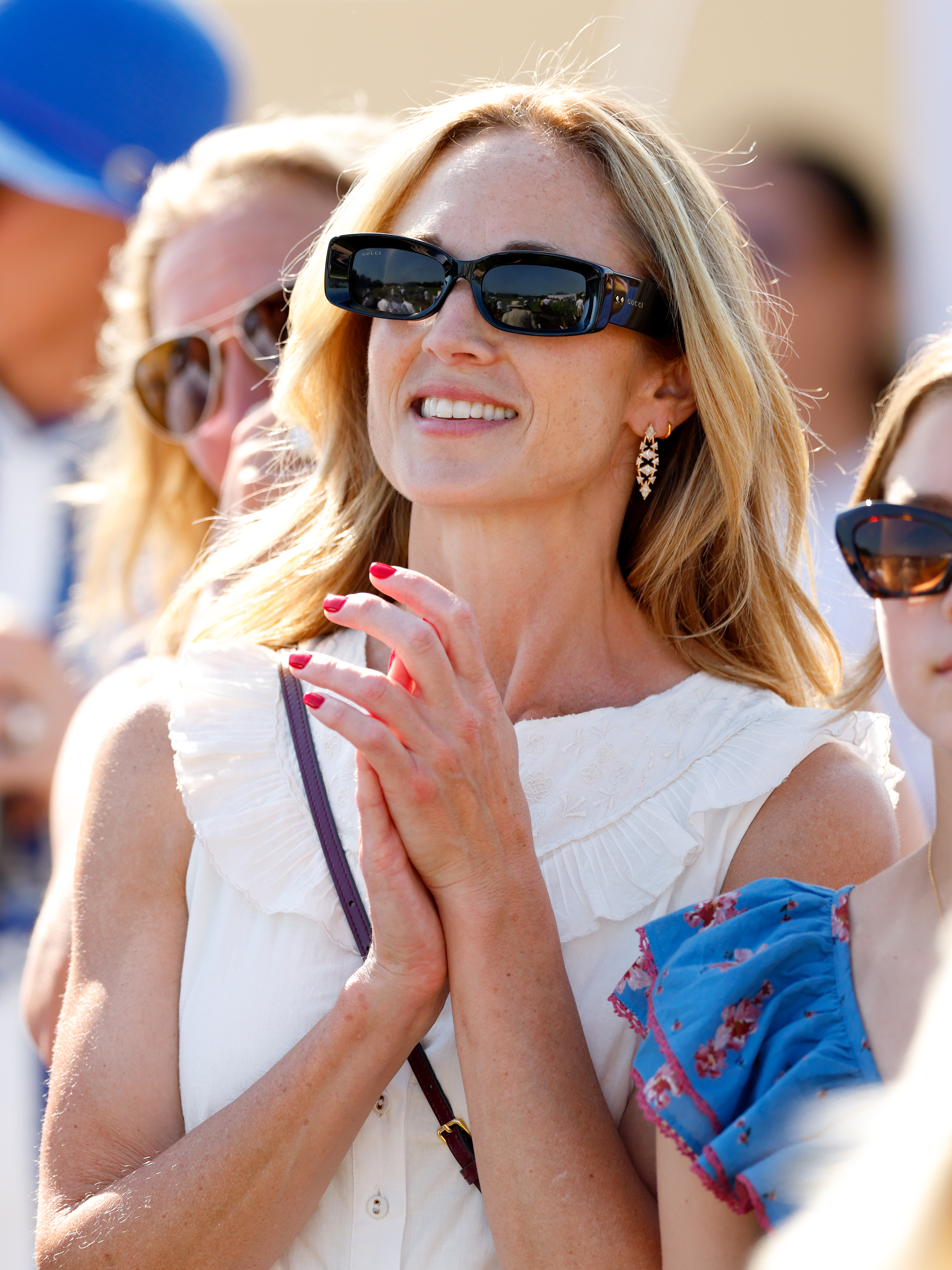 Harriet Sperling smiling wearing a white dress and sunglasses