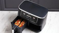 The Ninja Foodi Max Dual Drawer Air Fryer on a countertop with one drawer fully removed and one pulled out to show pizza inside