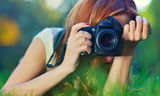 A women lying down on grass using one of the best cameras