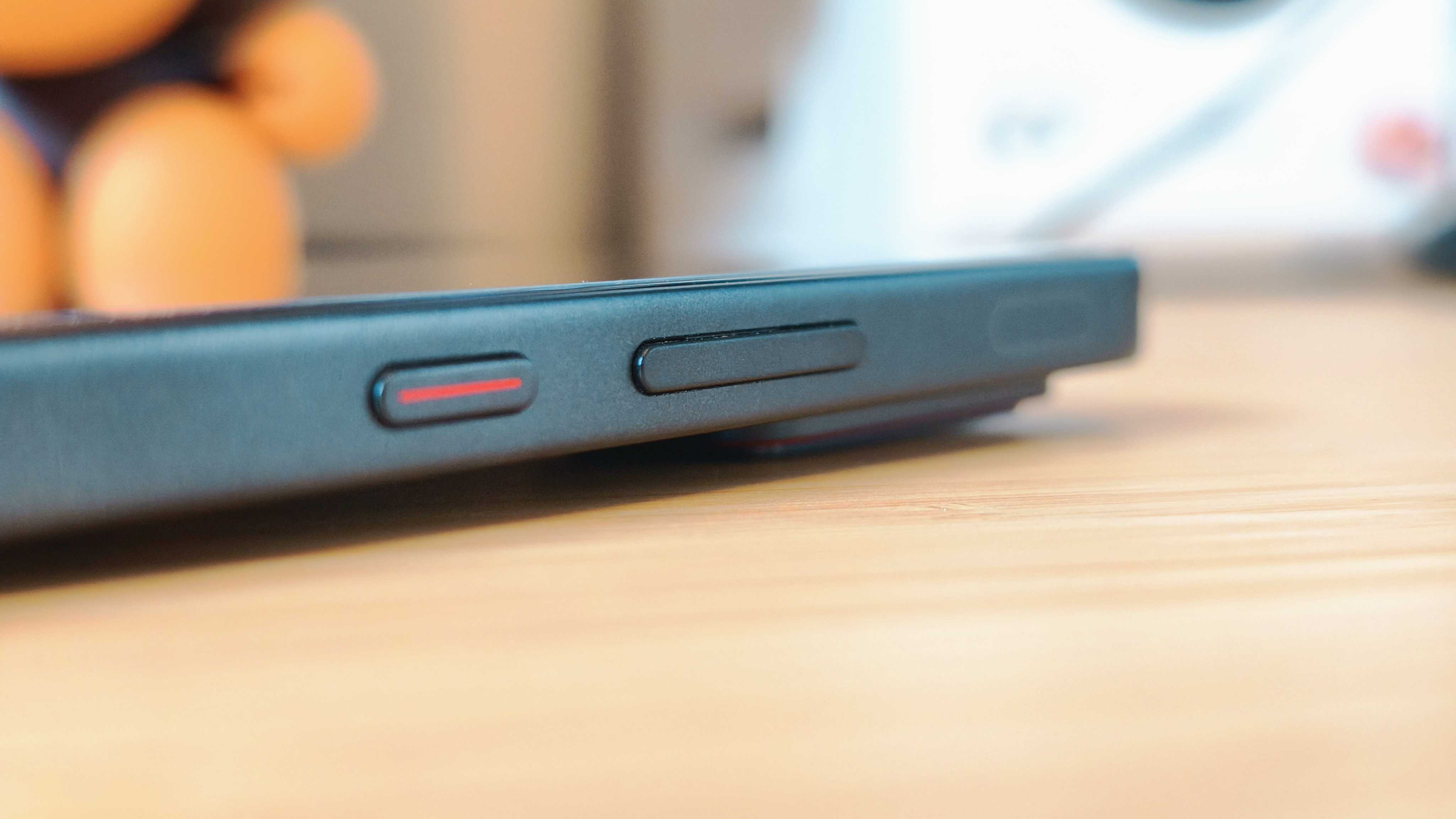 A black Infinix GT 30 Pro phone on a wooden desk