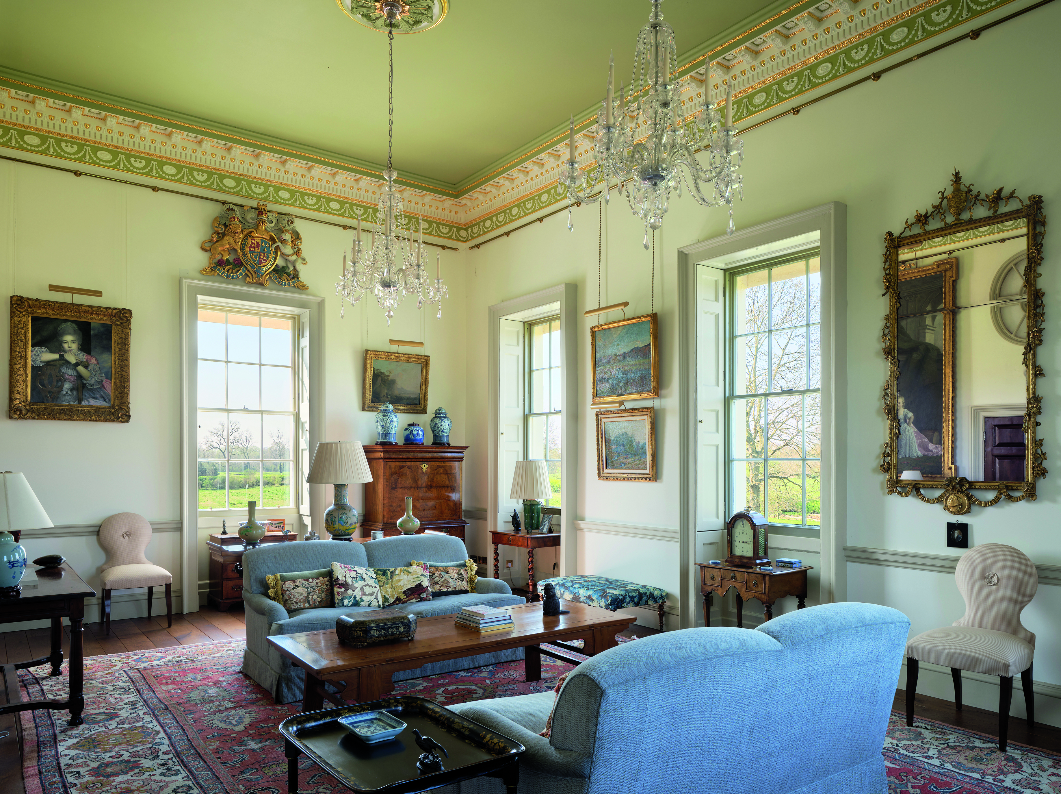 A living room with blue sofas, an ornate rug, mirrors and good light