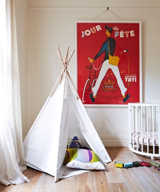 Gender neutral nursery with teepee, white cot and bright red wall art.