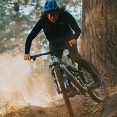 A cyclist riding a Specialized mountain bike on a trail through a wooded area