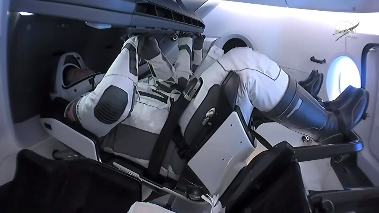 NASA astronauts Bob Behnken (foreground) and Doug Hurley sit inside their SpaceX Crew Dragon Demo-2 spacecraft before undocking from the International Space Station, on Aug. 1, 2020.