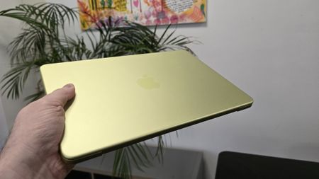 MacBook Neo laptop on a desk with plant in background