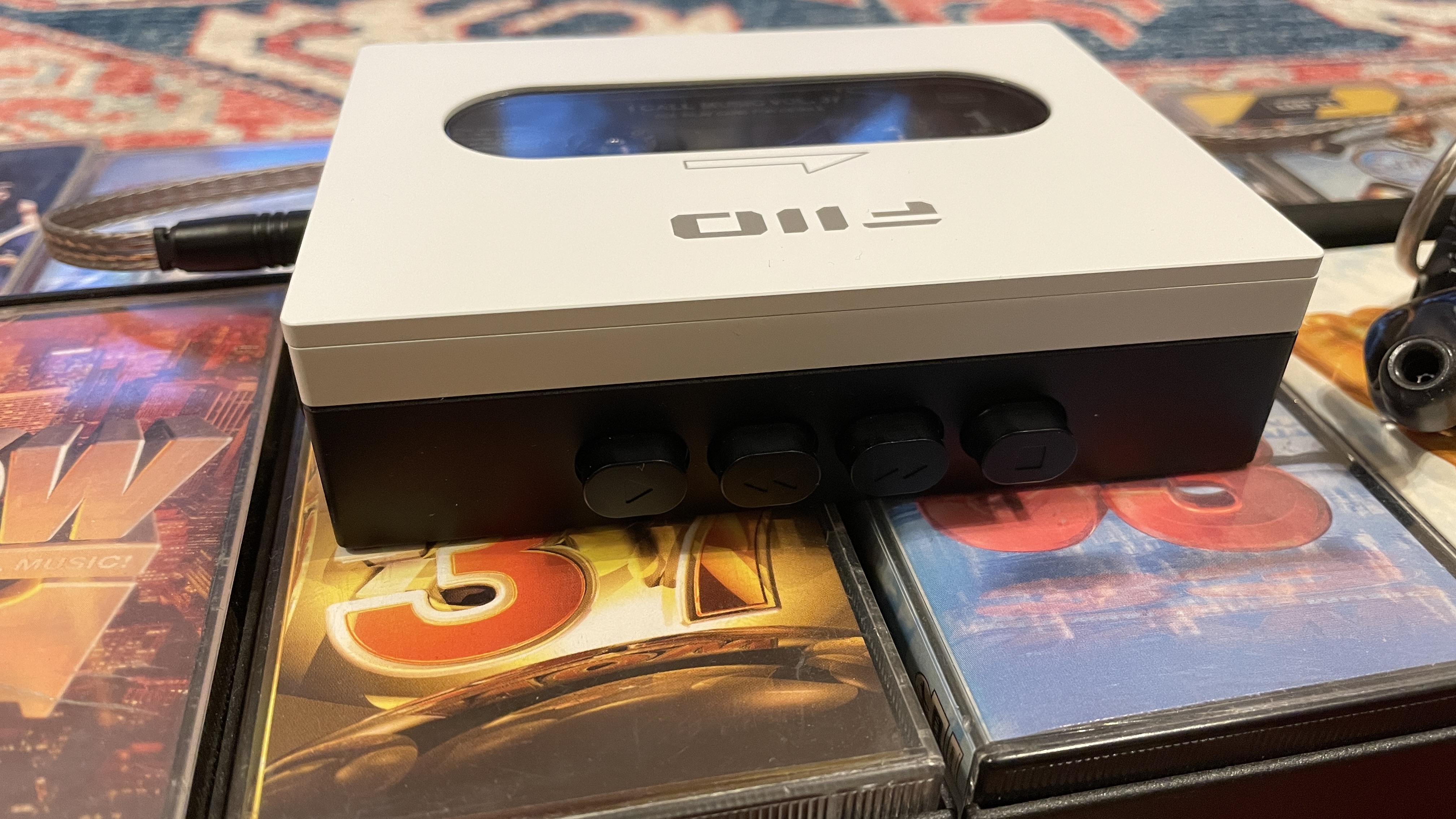 FiiO's CP13 with Campfire Audio Clara IEMs, on top of several cassette tapes, all on a colorful carpet