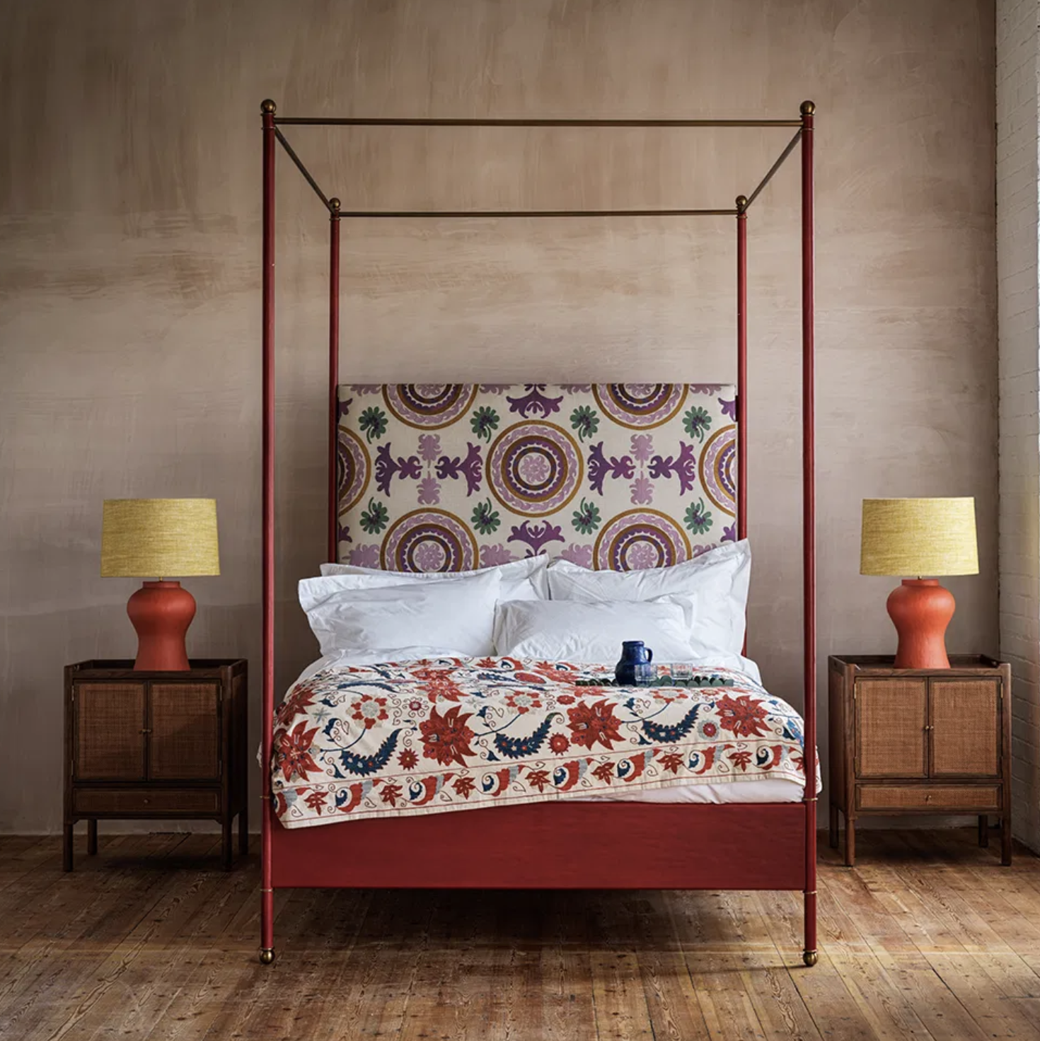 red bed with four poster frame and two matching red lamps