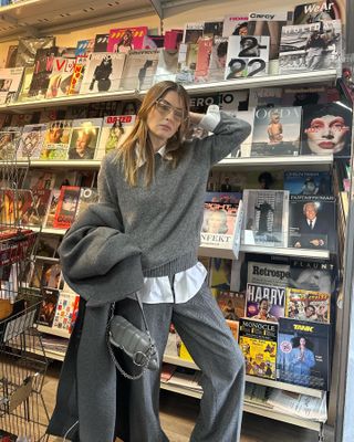 woman in front of newsstand wearing all-grey outfit