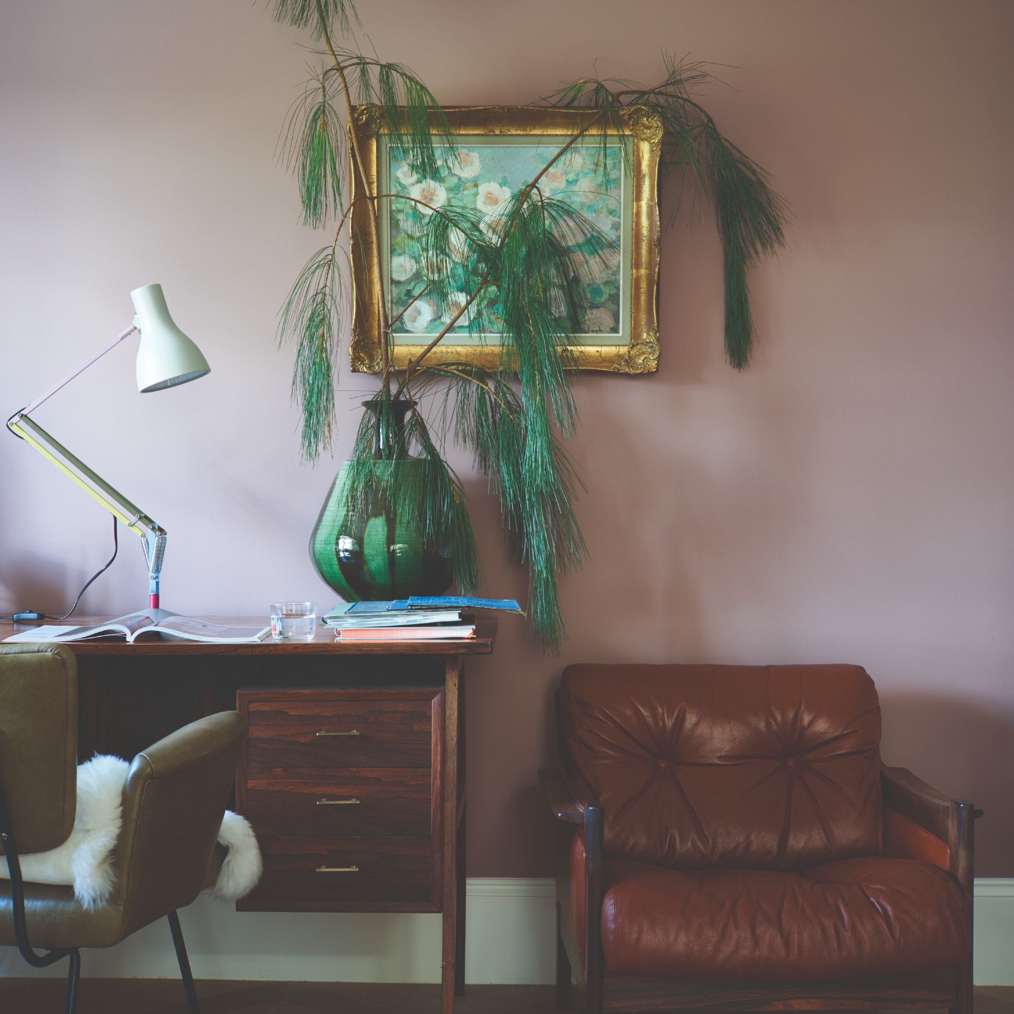 A home office with the wall painted in Farrow & Ball's Sulking Room Pink with a flower painting on the wall