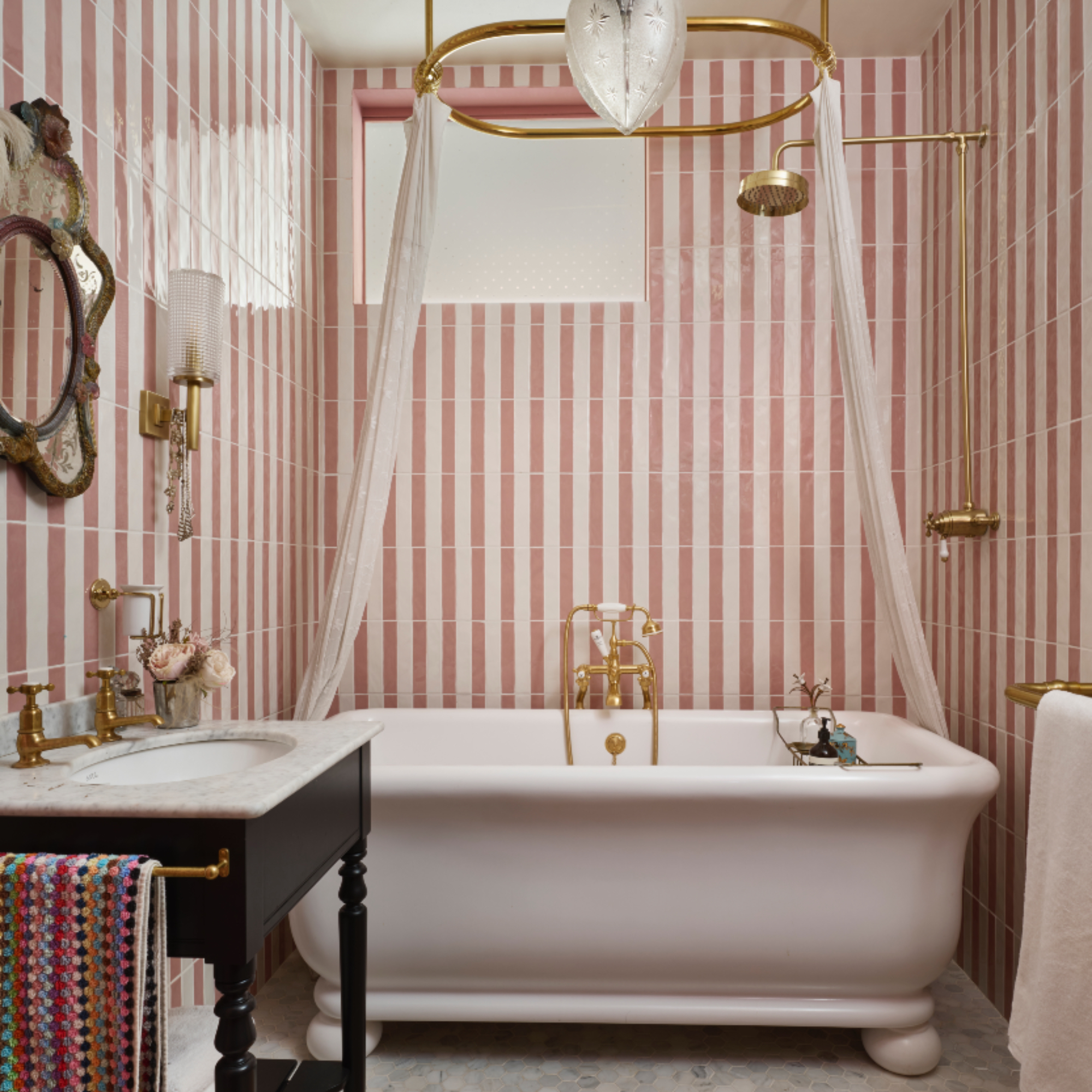 Pearl Lowe's bathroom with pink and white tiles, white classic bath, mahogany sink, vintage accessories