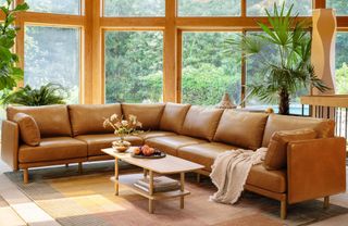 Large corner leather brown sofa in living room, wooden coffee table