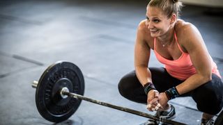Woman crouched next to barbell