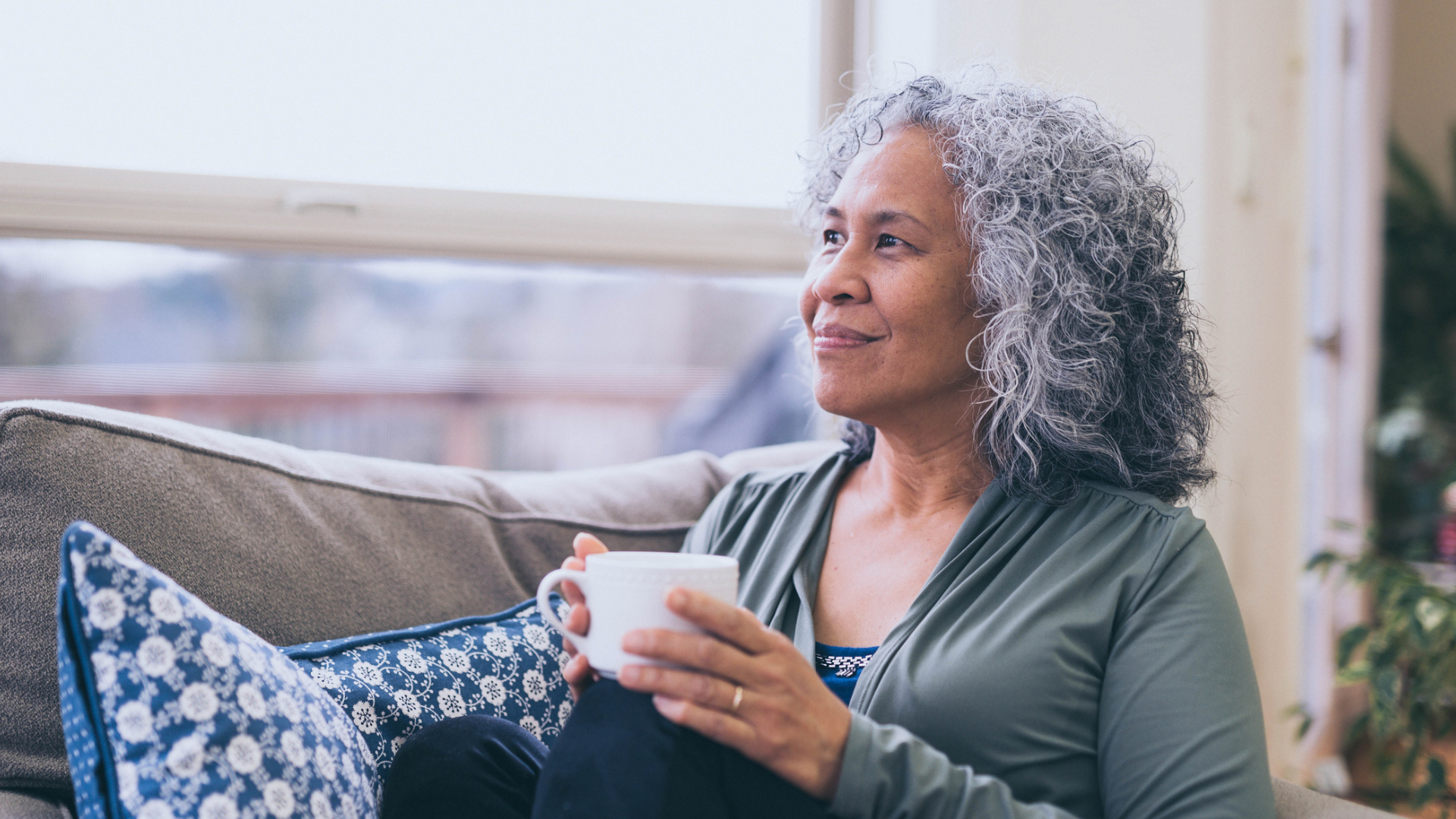 senior woman smiling as she drinks a cup of tea