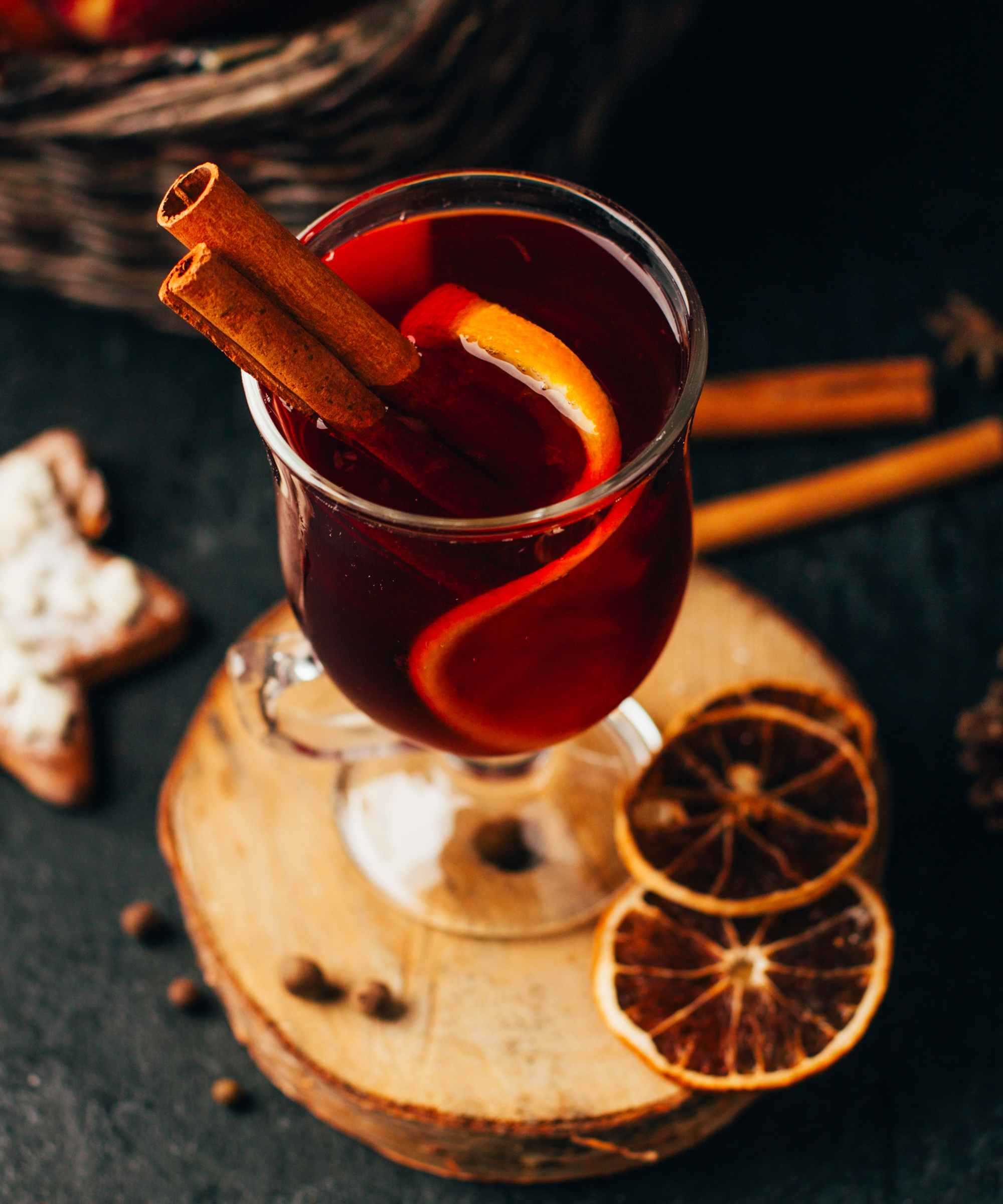 Close-up of a glass with mulled wine cinnamon and cardamom on a black background with ingredients for the drink - stock photo